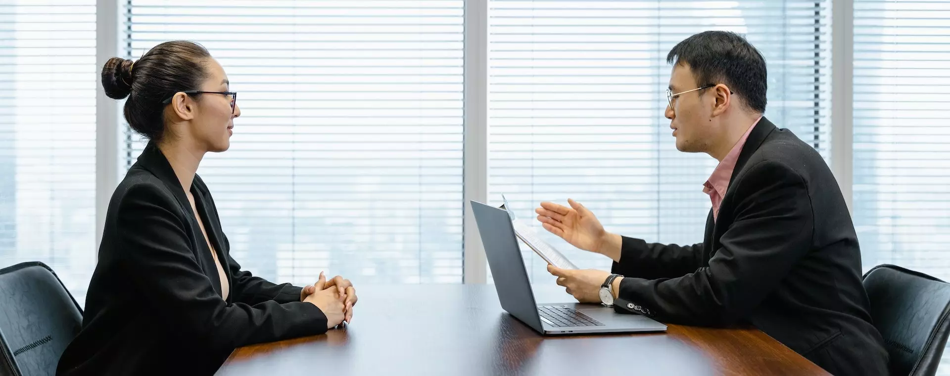 Male interviewer with laptop administering a case study to a female interviewee