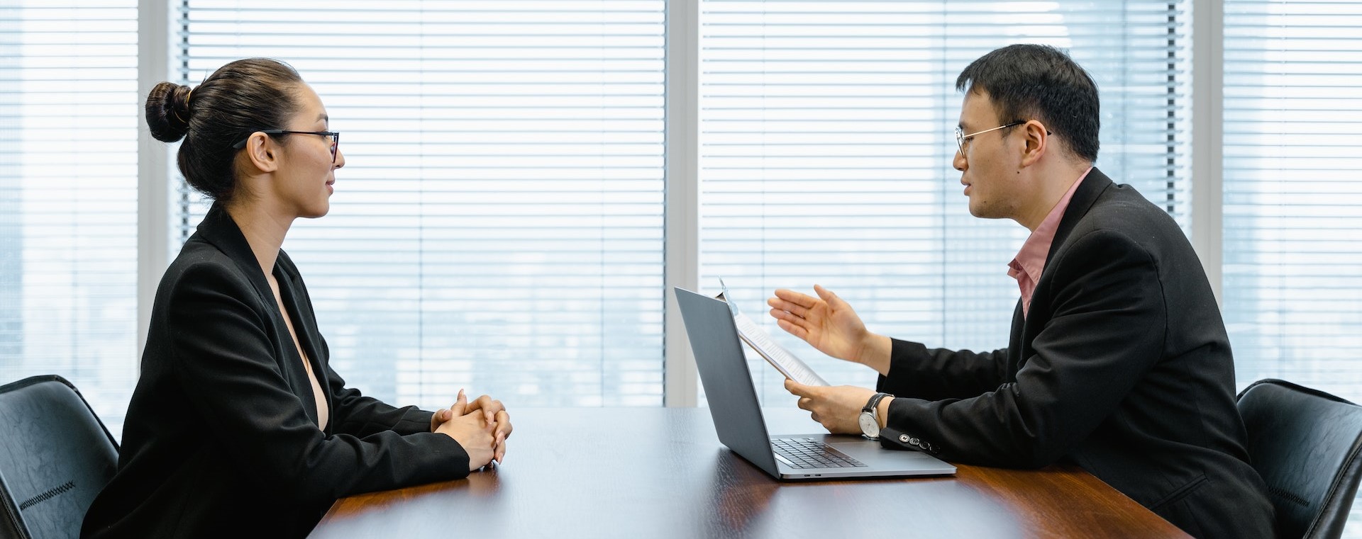 Male interviewer with laptop administering a case study to a female interviewee